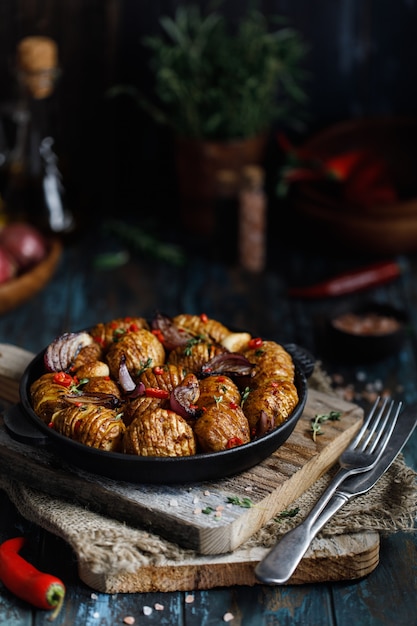 Baked potatoes in cast-iron pan with onion, garlic and herbs