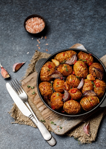 Baked potatoes in cast-iron pan with onion, garlic and herbs