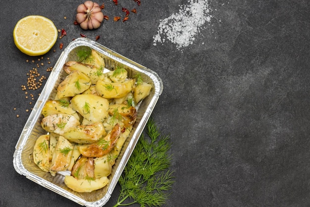 Baked potatoes in foil with dill Rosemary and green peppers garlic and lemon on table