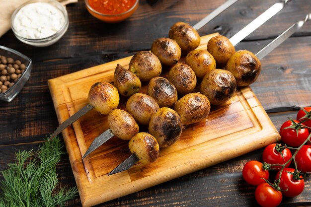 Baked potatoes grilled on skewers on cutting board rustic style