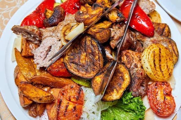 Baked potatoes and grilled vegetables with kebabs and sausages. Close-up, selective focus