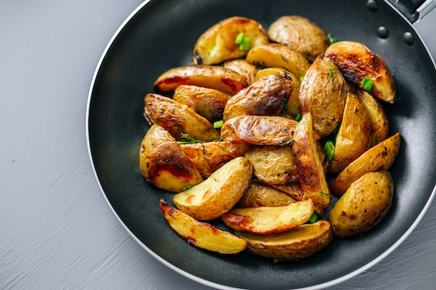 Baked potatoes in a pan on a gray background top view