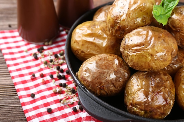 Baked potatoes in pan on wooden table closeup