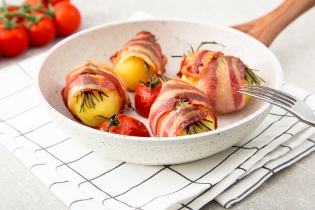 Baked potatoes with bacon, tomatoes and rosemary.