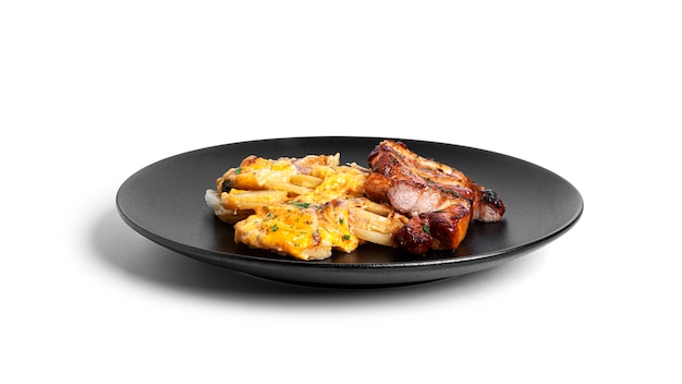 Baked potatoes with cheese and pork steak in black plate isolated.