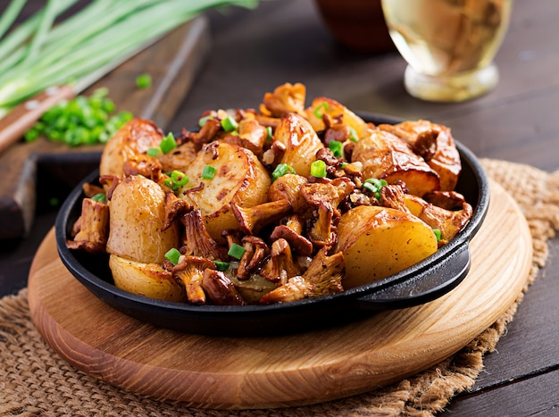 Baked potatoes with garlic, herbs and fried chanterelles in a cast iron skillet.