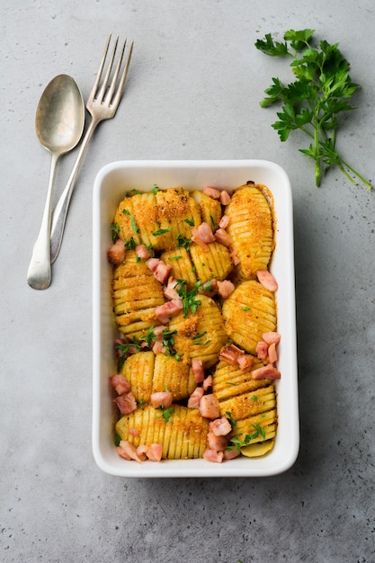 Baked potatoes with ham, herbs and breadcrumbs on gray light surface. Scandinavian cuisine. Top view.