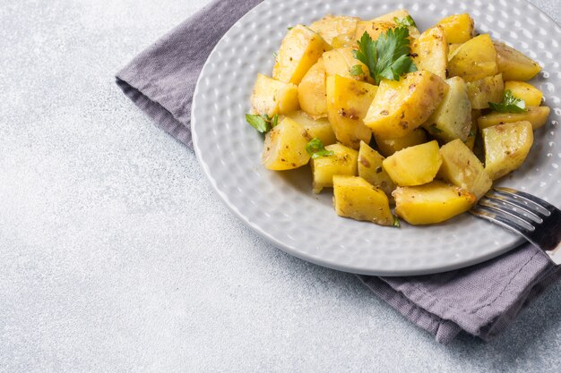 Baked potatoes with spices and herbs on a plate. Copy space.