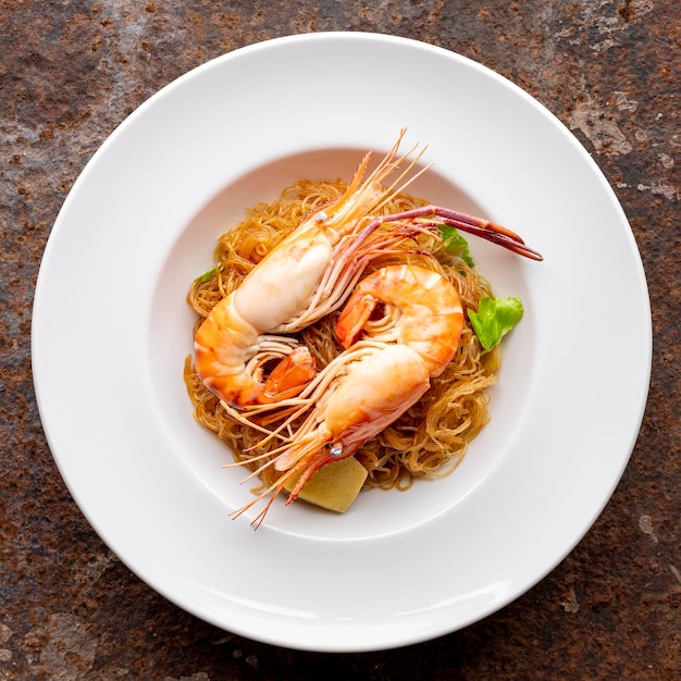 baked prawns with vermicelli casseroled shrimps with glass noodles in white simply ceramic plate on rusty texture background top view flat lay square ratio river prawn