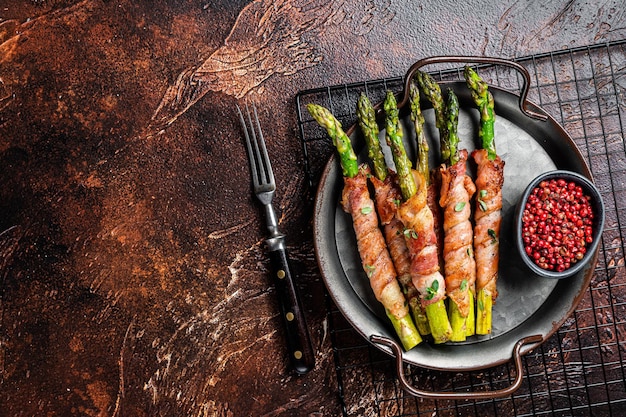 Baked Prosciutto wrapped green asparagus Dark background Top view Copy space