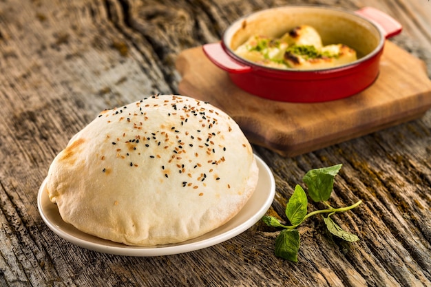 Baked puffed lavash bread on a plate wooden background