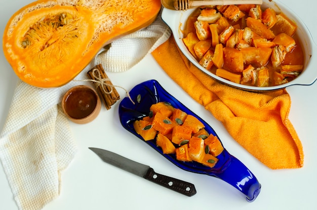 Baked pumpkin on a hand crafted blue serving plate on white background.