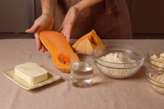 Photo baked pumpkin recipe for homemade cooking woman chef in brown kitchen apron hold sliced pumpkin