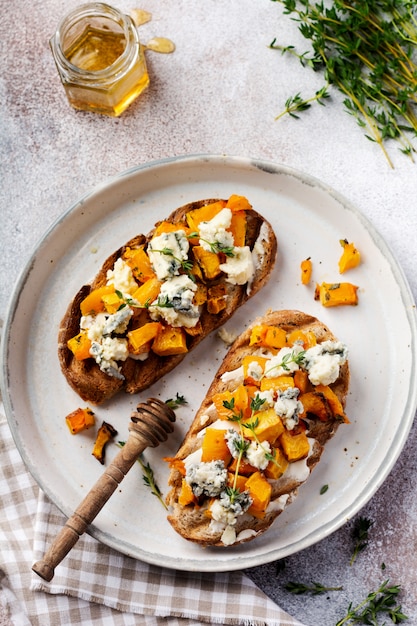 baked pumpkin sandwich with dorblu cheese with blue mold and thyme on a concrete background