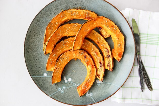 Baked pumpkin slices, sprinkled with dried herbs, drizzled with olive oil.