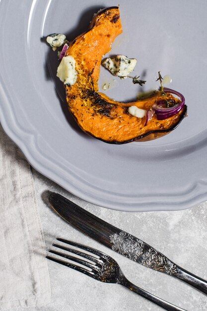 Baked pumpkin with Gorgonzola on grey plate.