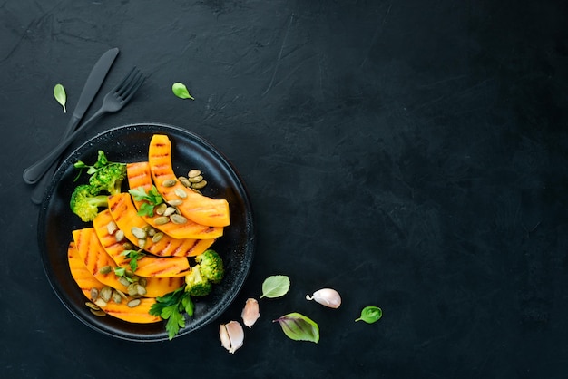 Baked pumpkin with pumpkin seeds and broccoli On a black background Top view Free space for your text