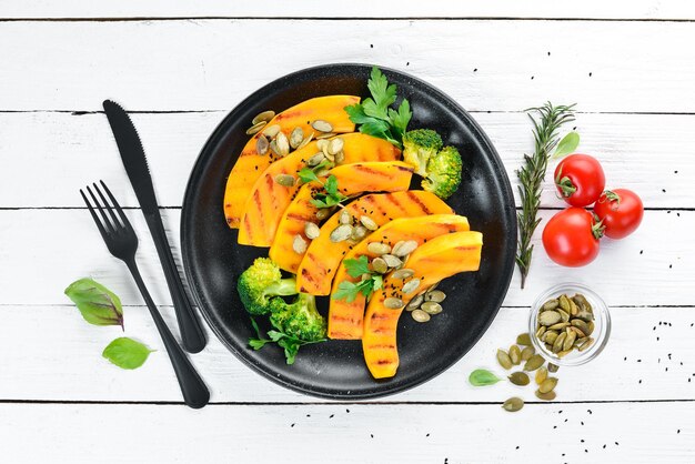 Baked pumpkin with pumpkin seeds and broccoli On a white wooden background Top view Free space for your text