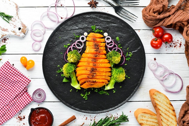 Zucca al forno con verdure su un piatto nero. vista dall'alto. spazio di copia gratuito.