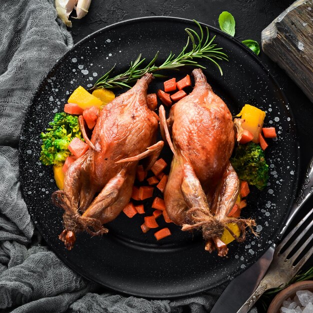 Baked quail On a black background Top view Free space for your text