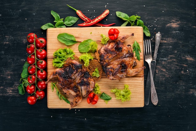 Baked quail with vegetables on a wooden board On a wooden background Top view Copy space