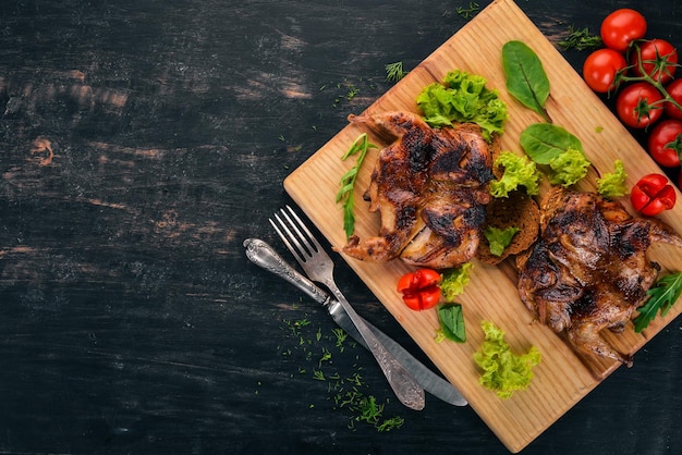 Baked quail with vegetables on a wooden board On a wooden background Top view Copy space