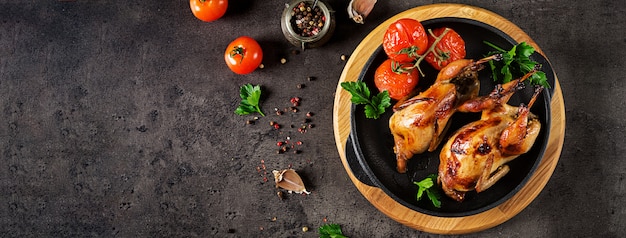 Baked quails in pan on a dark table