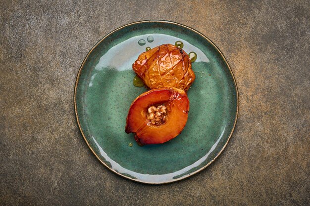 Baked quince with honey walnut and cinnamon on green plate on rustic background top view copy space