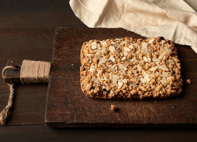 Baked rectangular crumble cake with fruit filling on wooden board