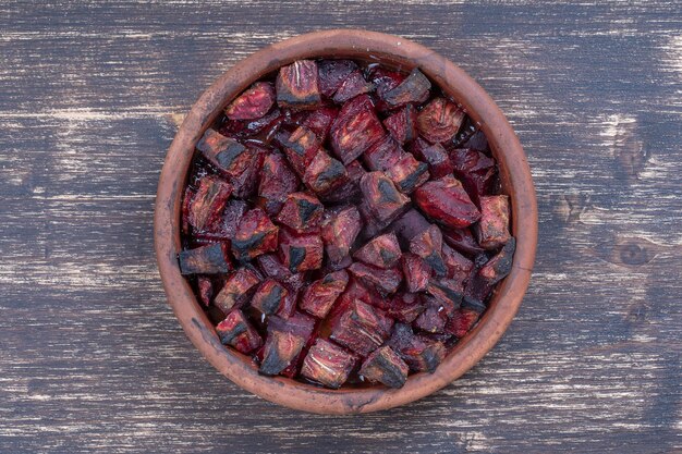 나무 테이블에 꿀을 넣은 구운 붉은 비트 뿌리 보라색 비트 조각이 있는 세라믹 그릇 배경 상단 보기