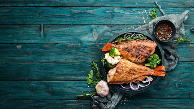 검은 돌 접시에 야채를 곁들인 구운 붉은 생선 농어 위쪽 보기 텍스트를 위한 여유 공간