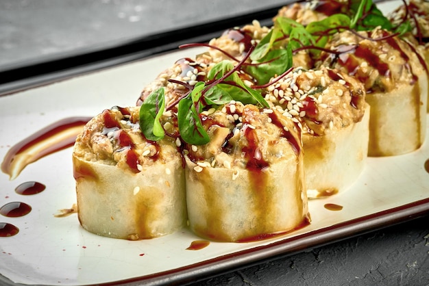 Baked roll with eel and unagi sauce in a white plate