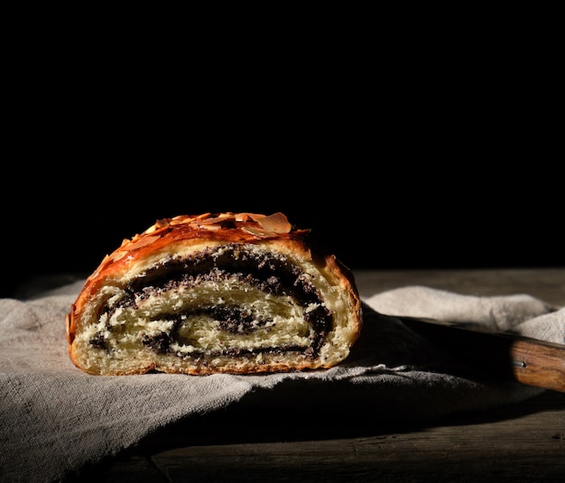 Rotolo al forno con semi di papavero sul tovagliolo di lino grigio