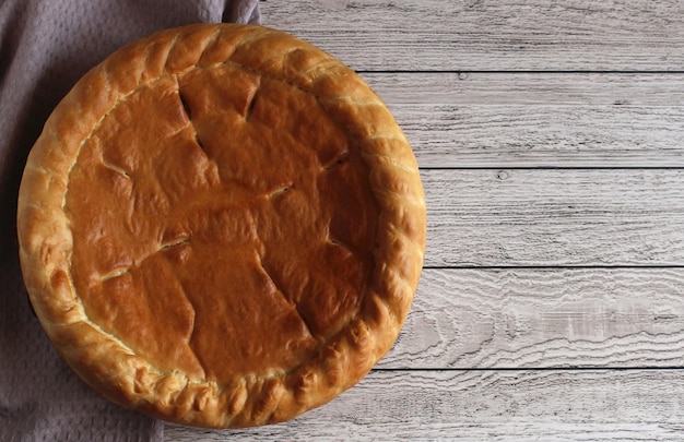 Baked round cake with filling on a wooden background top view