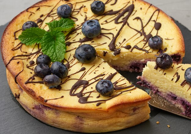 Baked round cottage cheese casserole on a black plate, top view