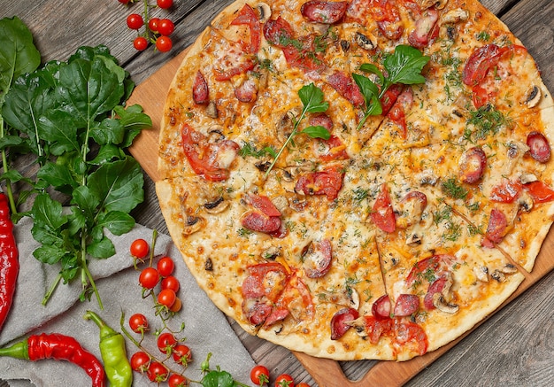 Baked round pizza with smoked sausages, mushrooms, tomatoes, cheese and arugula leaves