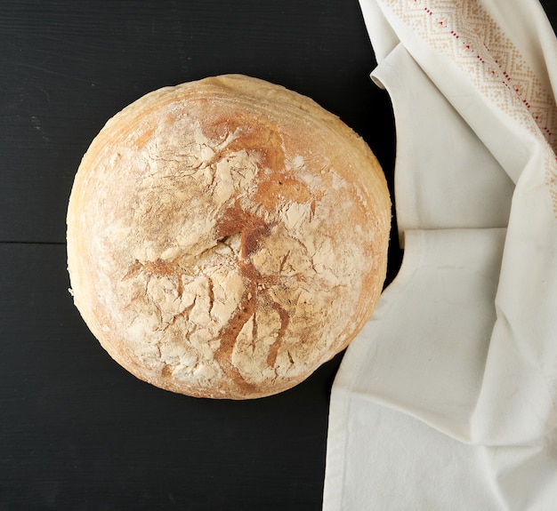 Baked round white wheat bread on a textile towel