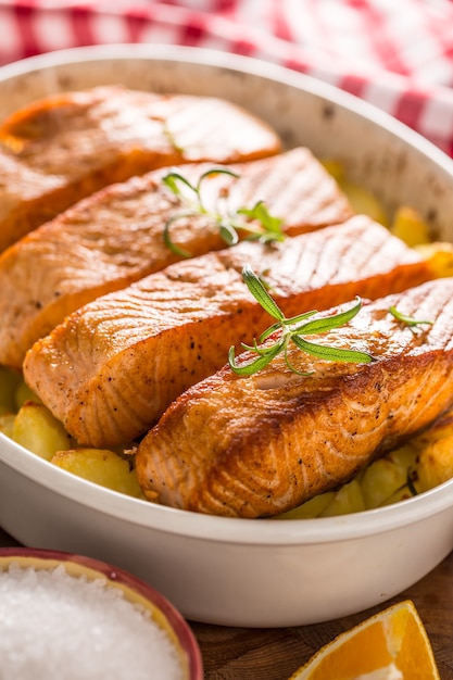 Baked salmon fillets with potatoes and herbs in a baking dish.