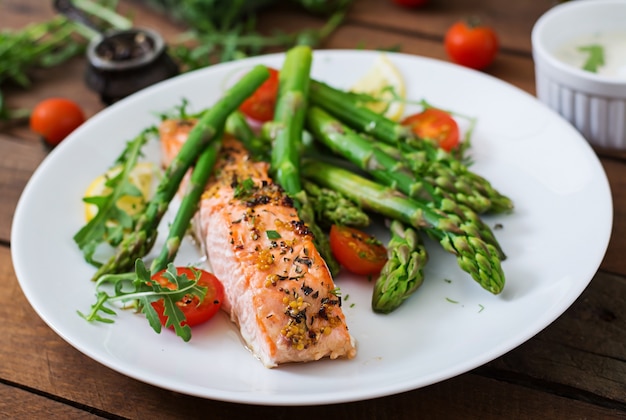 Baked salmon garnished with asparagus and tomatoes with herbs