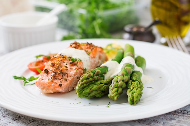 Baked salmon garnished with asparagus and tomatoes with herbs