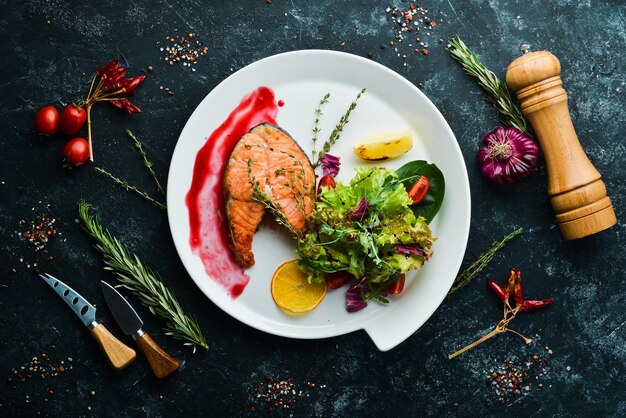 Baked salmon steak and fresh vegetables on a plate Top view Free copy space