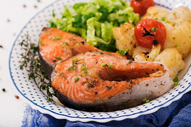 Baked salmon steak with cauliflower, tomatoes and herbs. Proper nutrition.