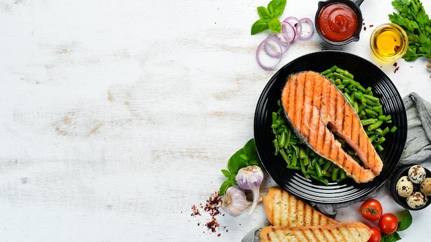 Baked salmon steak with green beans on a black plate Top view Free copy space