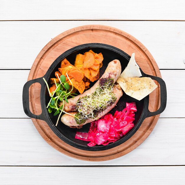 Baked sausages sweet potatoes and cabbage In the plate Top view Free space for your text Rustic style