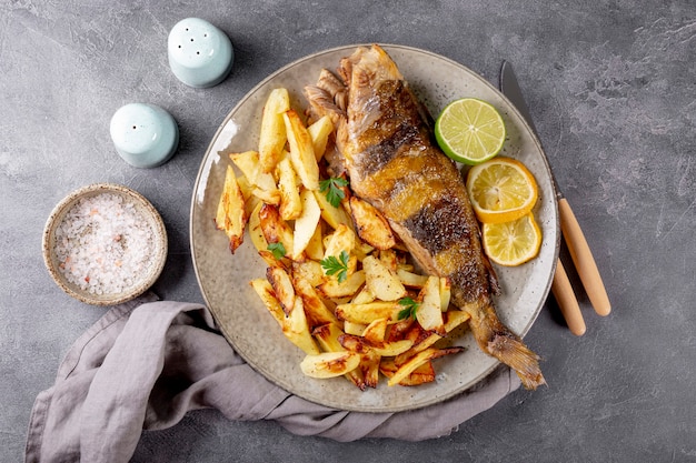 Baked sea bass or lingcod fish with potatoes on a plate and gray background