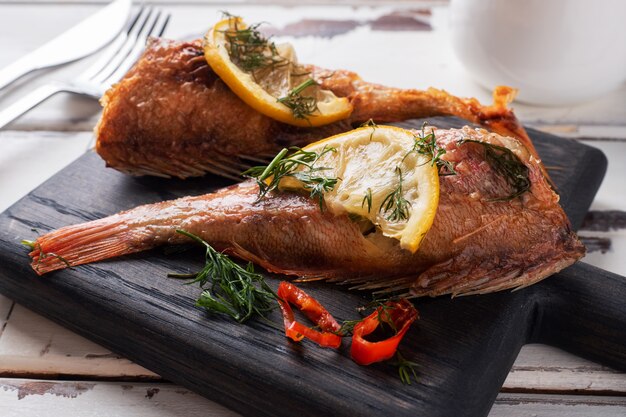 Baked sea bass with tomato pepper lemon and herbs on wooden Board