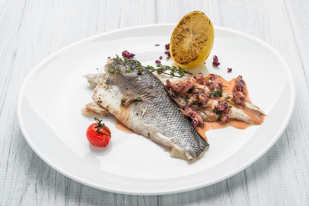 Baked sea bass with vegetables close up shoot on wooden surface