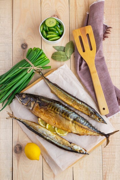 木製の背景に焼き海魚（サンマ、サバ）。上面図。