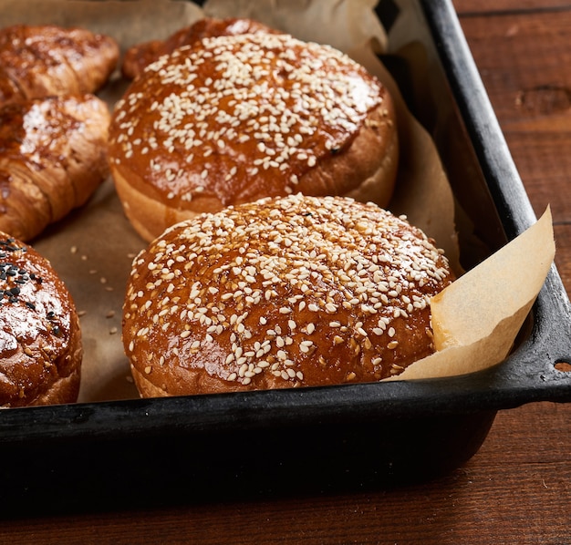 Baked sesame buns on brown parchment