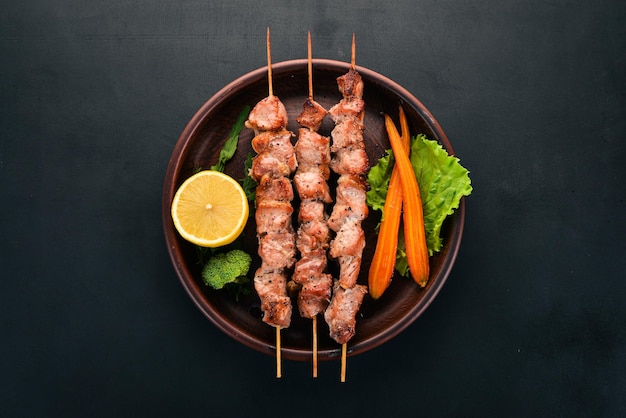 Baked Skewers of meat on a plate On a wooden background Top view Copy space